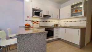 Une cuisine moderne avec des meubles blancs, un plan de travail en granit, un four à micro-ondes et un évier.