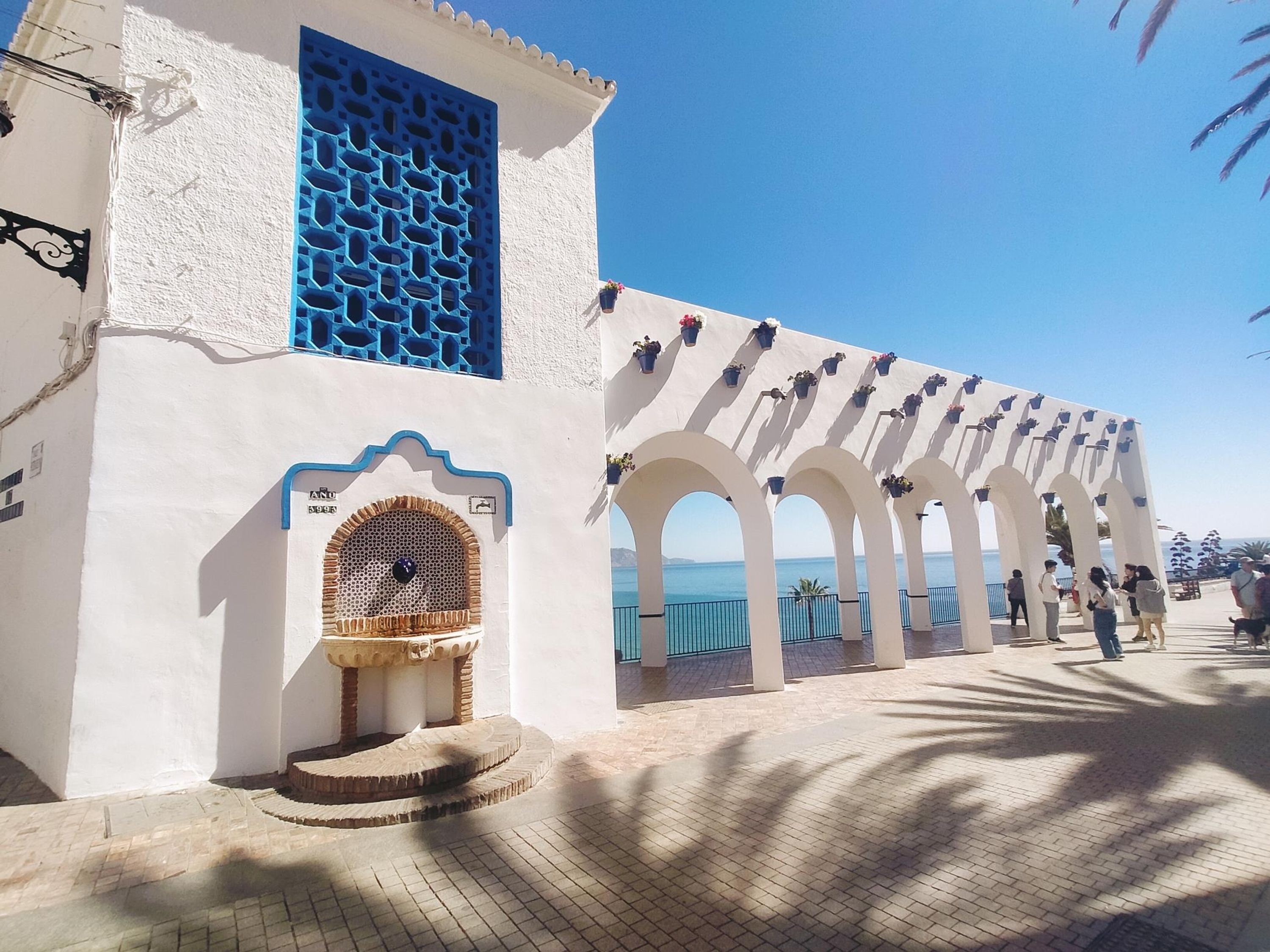 Un bâtiment situé sur la côte, avec des murs blancs, des volets bleus et une entrée carrelée.