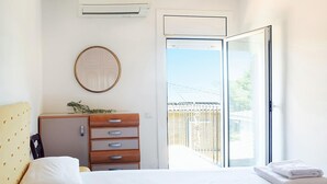 Een hotelkamer met een bed, een dressoir, een spiegel en een schuifdeur naar een balkon.