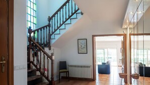 Een ruime woonkamer met een houten trap, een radiator en uitzicht op de aangrenzende kamer.