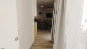 A hallway leading to a living area with a sofa and a TV. - Apartamento Bronce B Centro Nerja Sun (Nerja)
