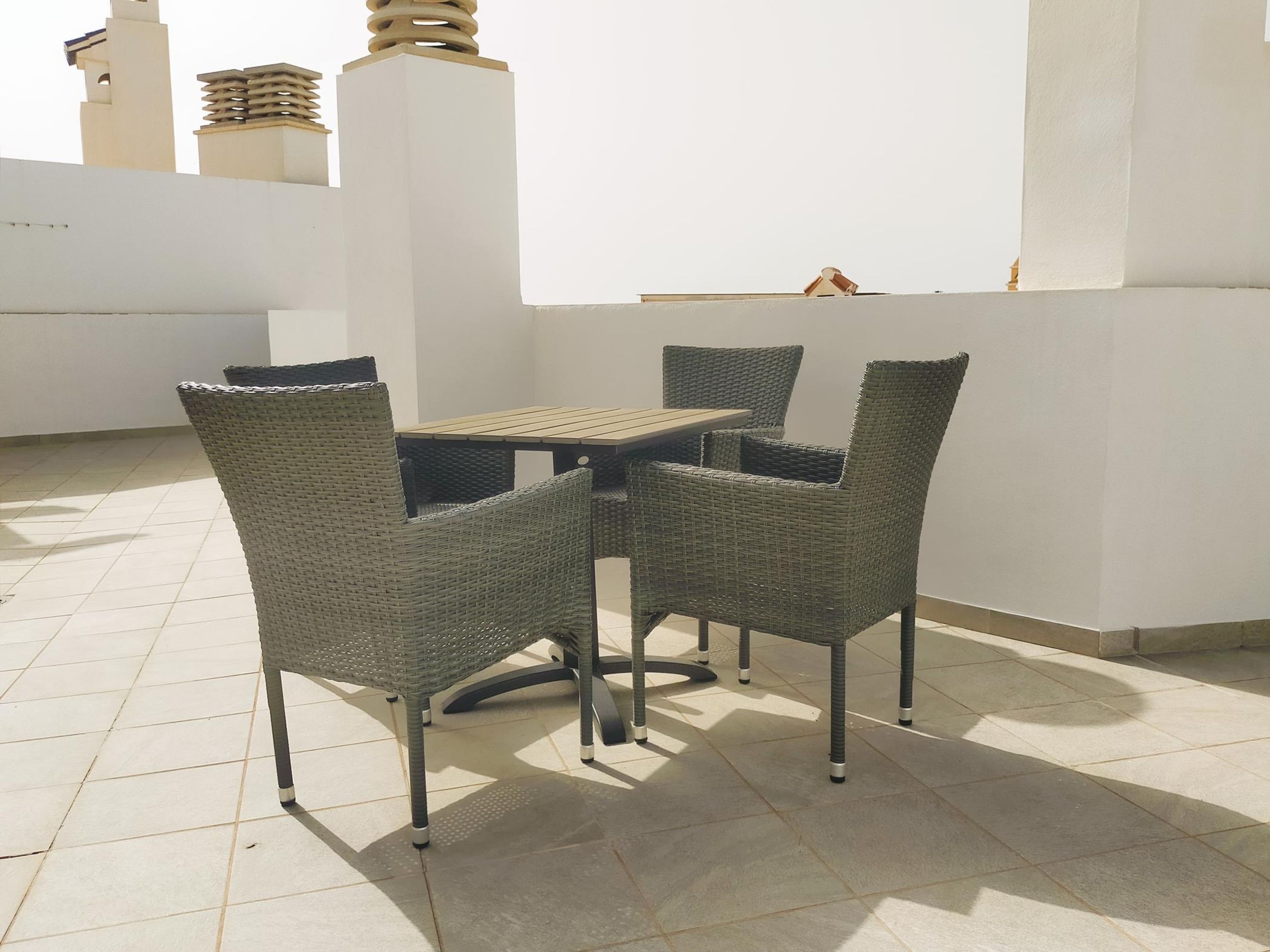 A patio with a table and four wicker chairs.
