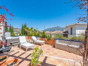 A rooftop terrace with lounge chairs, a hot tub, and potted plants.