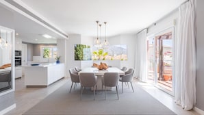 A modern kitchen with a central island, a dining area with a large table and chairs, and a view of a mountainous landscape through a window.