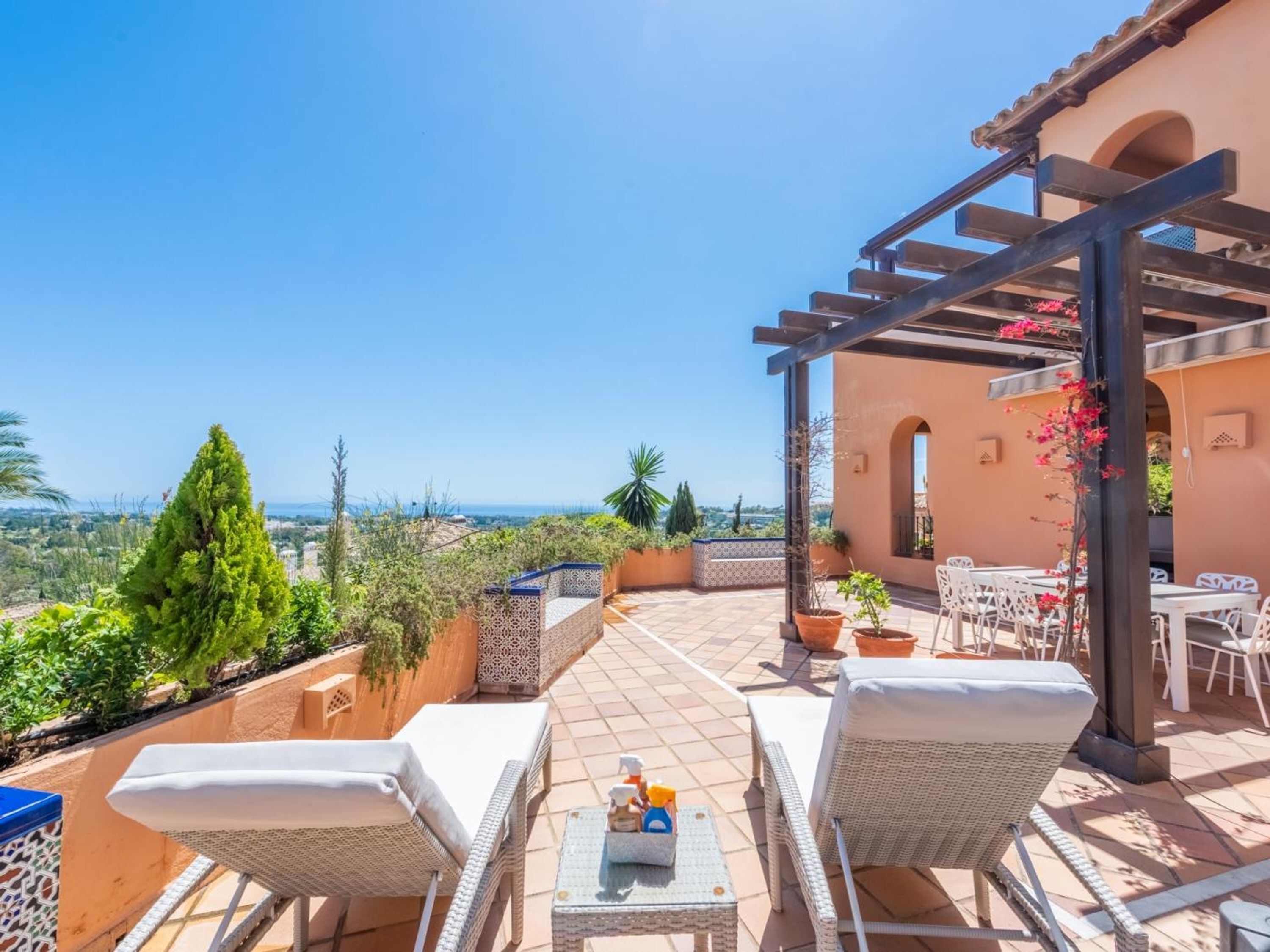 Una terraza con mobiliario de mimbre, vistas al mar y plantas en macetas.