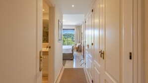 Ein Flur mit Blick auf einen Balkon, ein Badezimmer mit Dusche und ein Bett mit Aussicht.