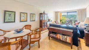 Ein Wohnzimmer mit Essbereich, einer Bücherwand und Blick ins Freie.
