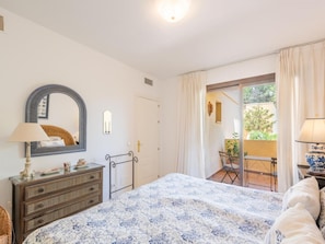 A bedroom with a bed, dresser, mirror, and a view of an outdoor patio.
