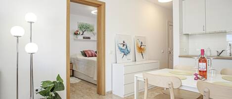 A modern, well-lit room with a dining table, chairs, a potted plant, and artwork on the wall.