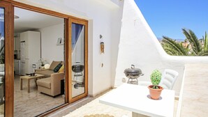 A modern outdoor dining area with a white table and chairs, a small potted plant, and a grill. - Sand Club Apartment 202 (San Miguel de Abona)