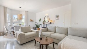 Una sala de estar moderna con un sofá, sillones, una mesa de centro y un comedor con mesa y sillas.
