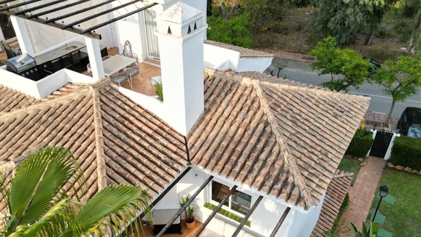 Una terraza en la azotea con pérgola, mobiliario exterior y vistas al entorno verde.