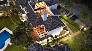 Un edificio residencial de varios pisos con piscina, rodeado de palmeras y un césped bien cuidado.