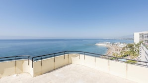 Een balkon met helder uitzicht op zee en een strand.