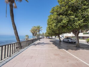 A paved walkway along a coastal area with palm trees, a parked car, and a clear blue sky. - Front Line Beach in Marbella (Marbella)