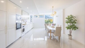 Een moderne keuken met een eethoek, een wasmachine en een potplant.