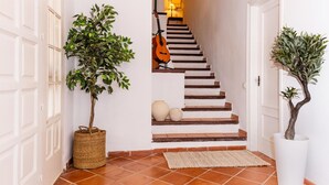 A staircase with a guitar leaning against the wall, a potted plant, and a textured rug on a tiled floor. - Charming Villa Domingo Playa Portaventura Golf (Cambrils)