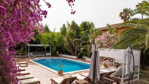 A pool area with lounge chairs, a pergola, and a covered seating area. - Charming Villa Domingo Playa Portaventura Golf (Cambrils)