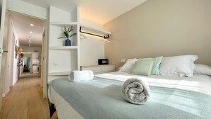 A modern bedroom with a large bed, a walk-in closet, and a bathroom visible through an open door. - Precioso Tico Cerca de la Playa y Port Aventura (Salou)