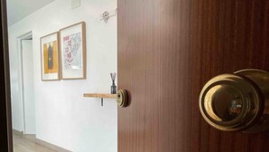 A hallway with a wooden door, a framed map on the wall, and a small shelf with a container. - Fabuloso Apartamento Cerca Playa y Portaventura (Salou)