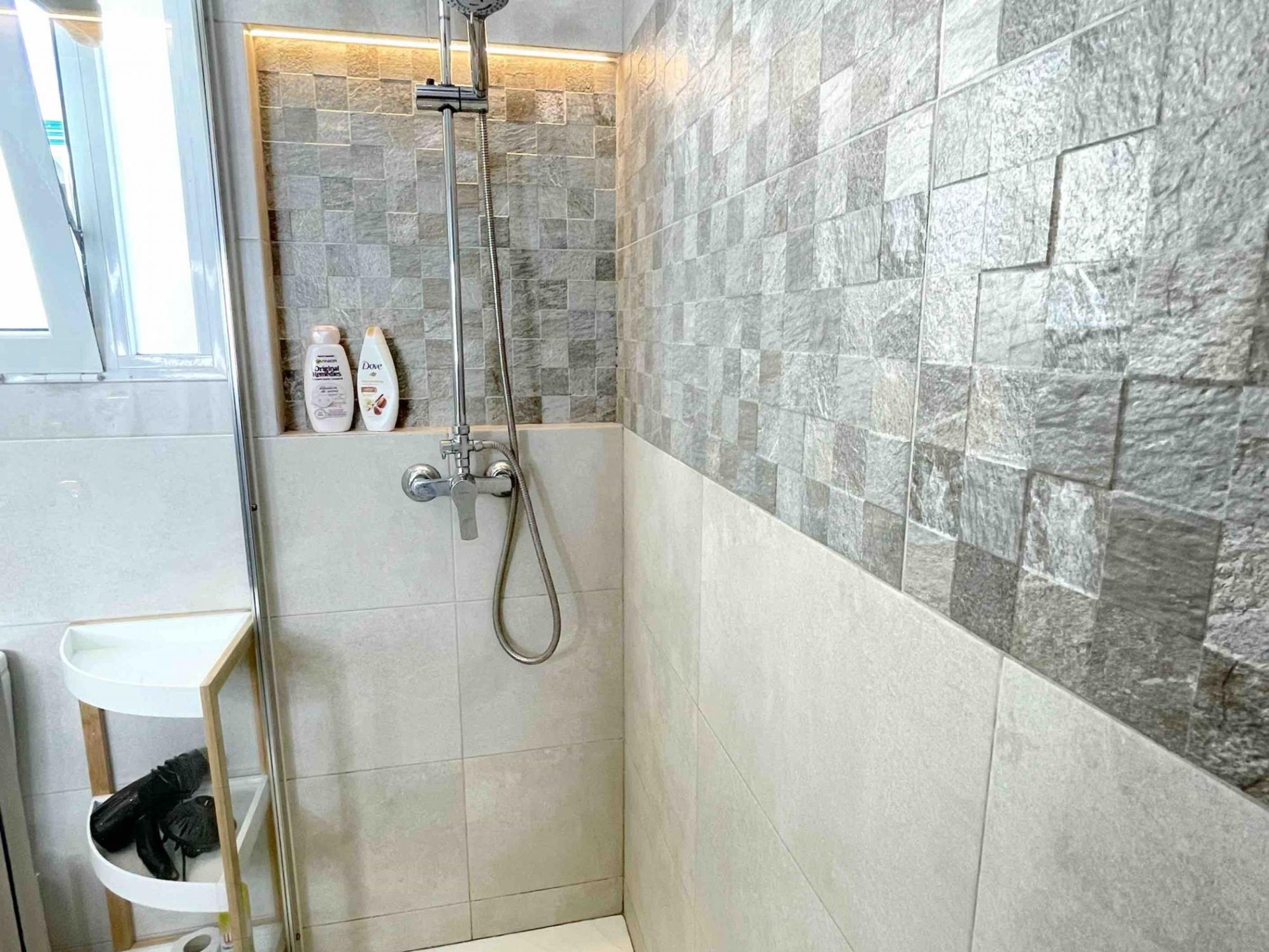 A bathroom with a shower, tiled walls, and a sink.
