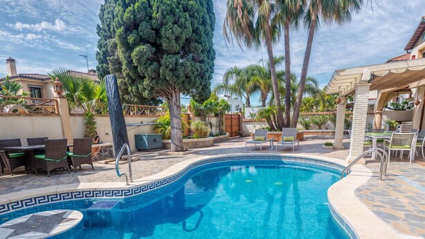 Una piscina con bordi decorativi, circondata da lettini e palme.