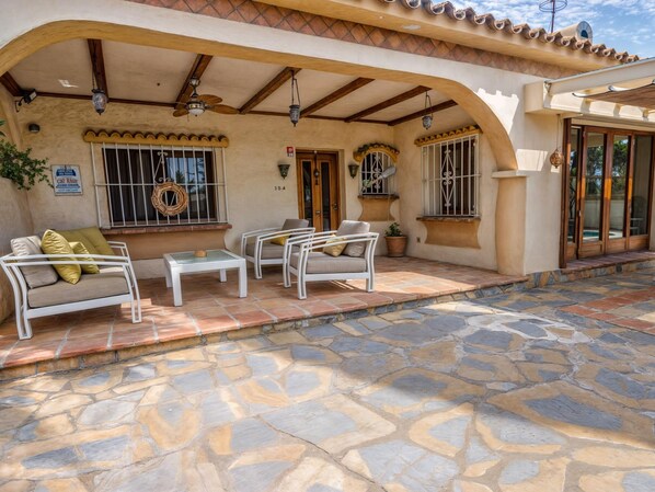 A patio area with stone flooring, white outdoor furniture, and a ceiling fan. - Villa Luna in Estepona (Estepona)