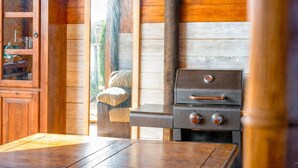 A wooden interior with a built-in wood stove, a cabinet with glass doors, and a wooden table. - Casa Stardust in El Palmar- Vejer de la Frontera (Vejer de la Frontera)