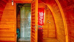 A wooden room with a bed, a door leading to a shower, and a small cabinet. - Casa Stardust in El Palmar- Vejer de la Frontera (Vejer de la Frontera)