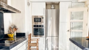 Una cocina moderna con horno empotrado, microondas y refrigerador de acero inoxidable.