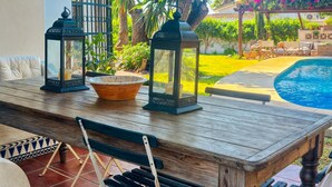 Un área de comedor al aire libre con una mesa de madera, dos faroles y un cuenco.