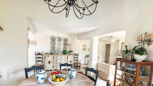 Un comedor con una mesa redonda de madera, cuencos de cerámica azul y blanca, y un candelabro.