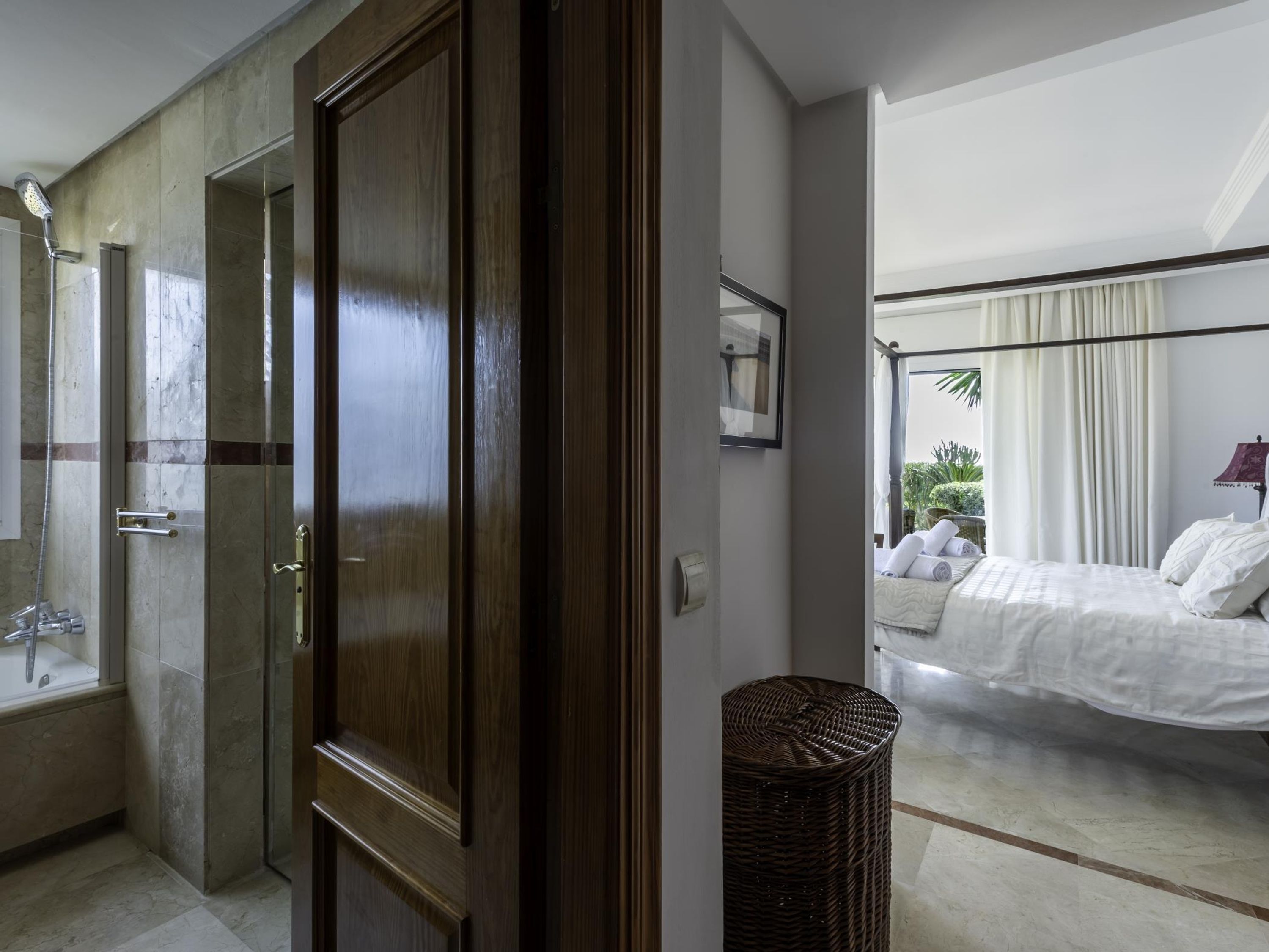 A modern bathroom with a shower, a bathtub, and a toilet. There is a wicker basket on the floor.