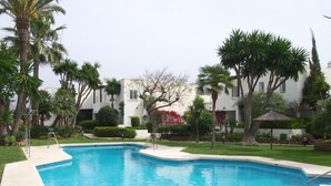 A rectangular swimming pool with a clear blue water, surrounded by a concrete deck.