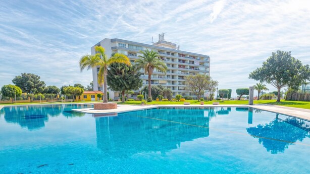 Una piscina amplia y despejada con un edificio moderno al fondo.