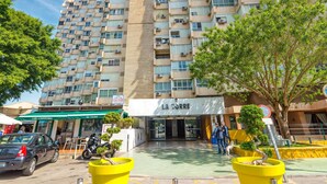 Un edificio de gran altura con varios balcones, entrada a nivel de calle y un restaurante visible llamado "La Torre".