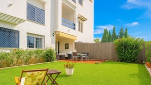 A two-story house with a balcony, a patio with a table and chairs, and a well-maintained lawn.