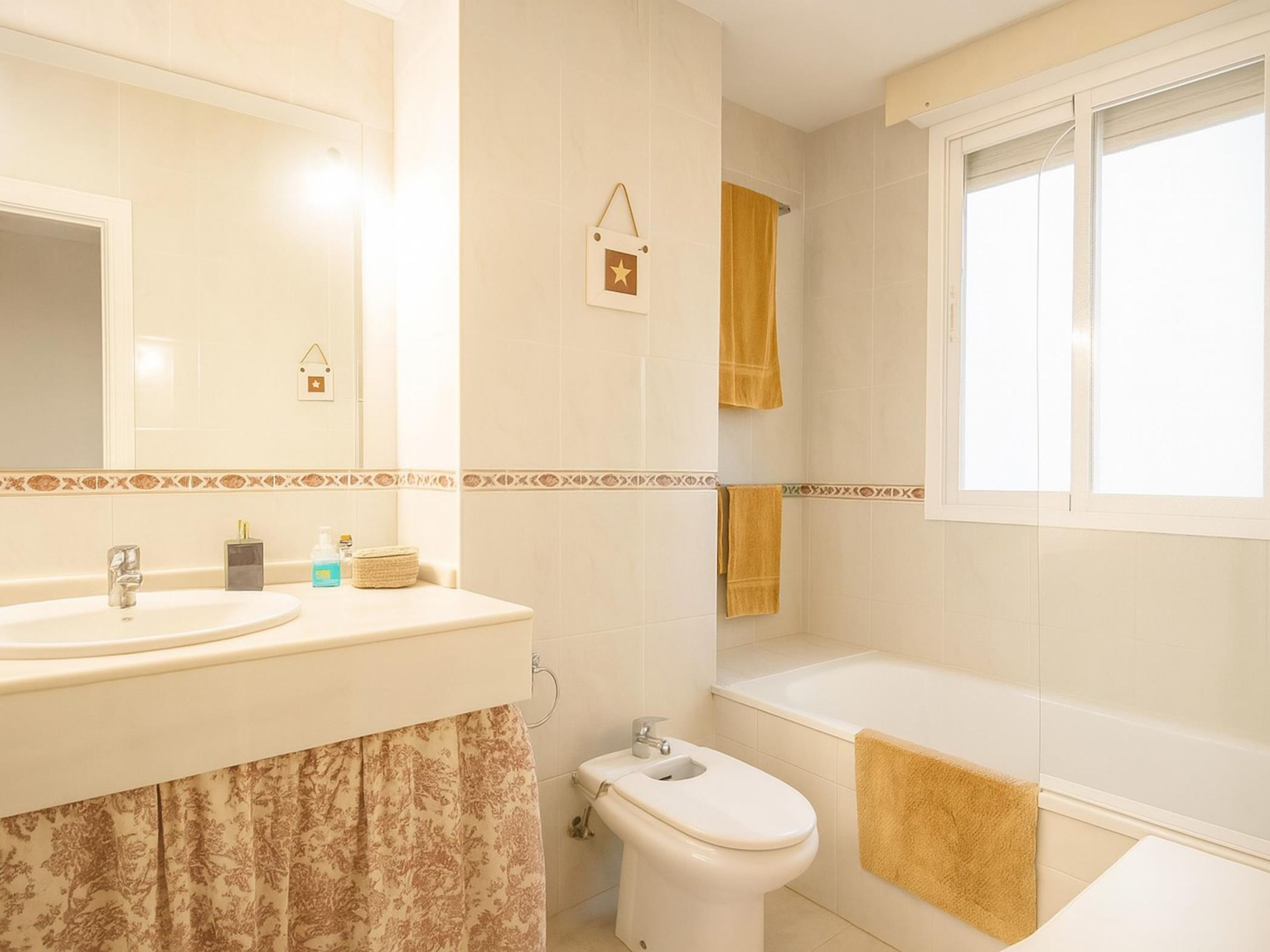 Un baño con un espejo grande, dos lavamanos, un inodoro y una bañera.