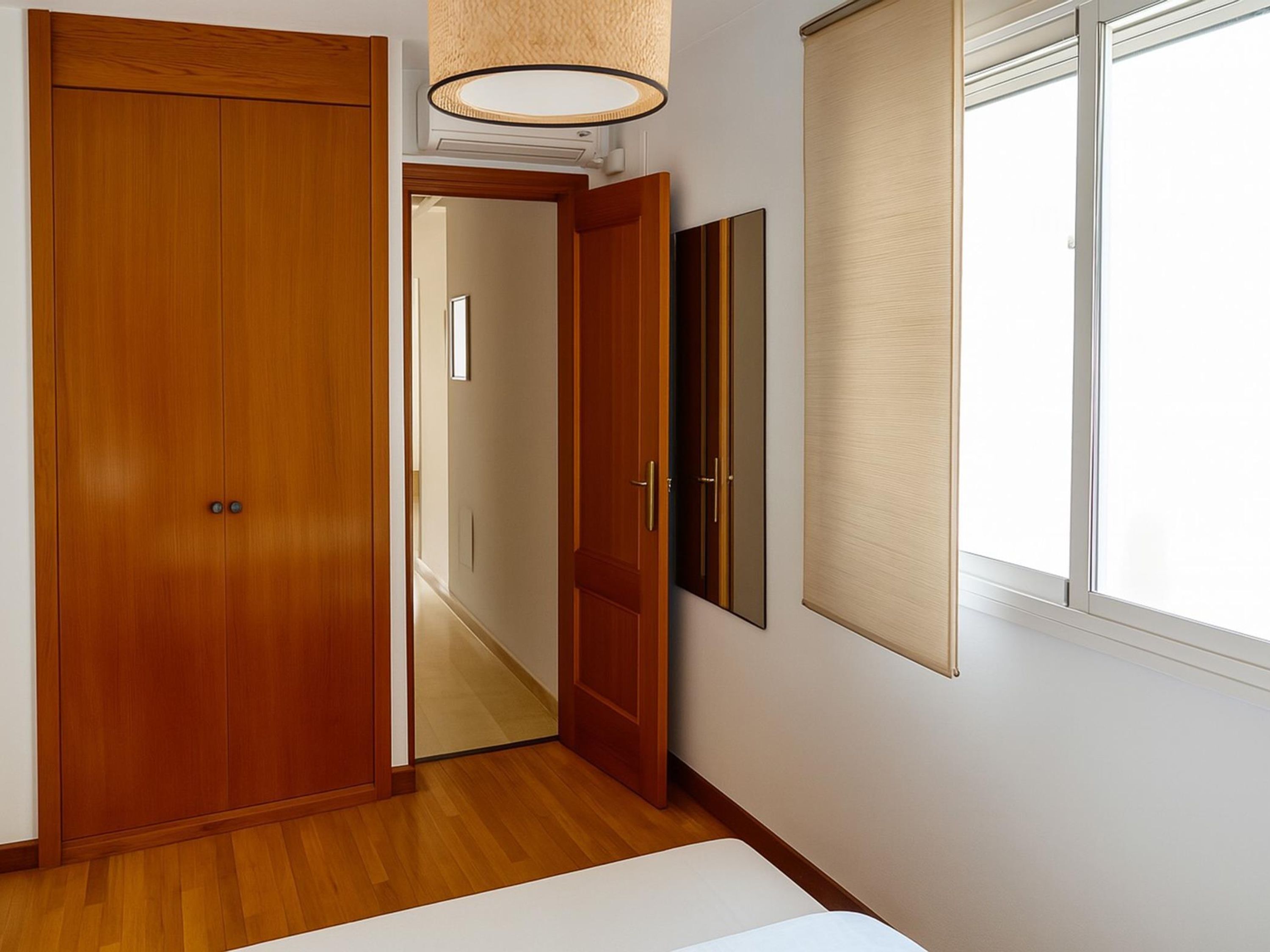 Una habitación con un armario de madera, un espejo y una ventana con persianas.