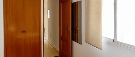 Una habitación con un armario de madera, un espejo y una ventana con persianas.
