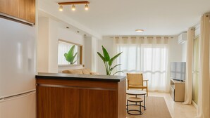 Une cuisine moderne avec des meubles en bois, un îlot central et un coin repas comprenant une chaise et une table.