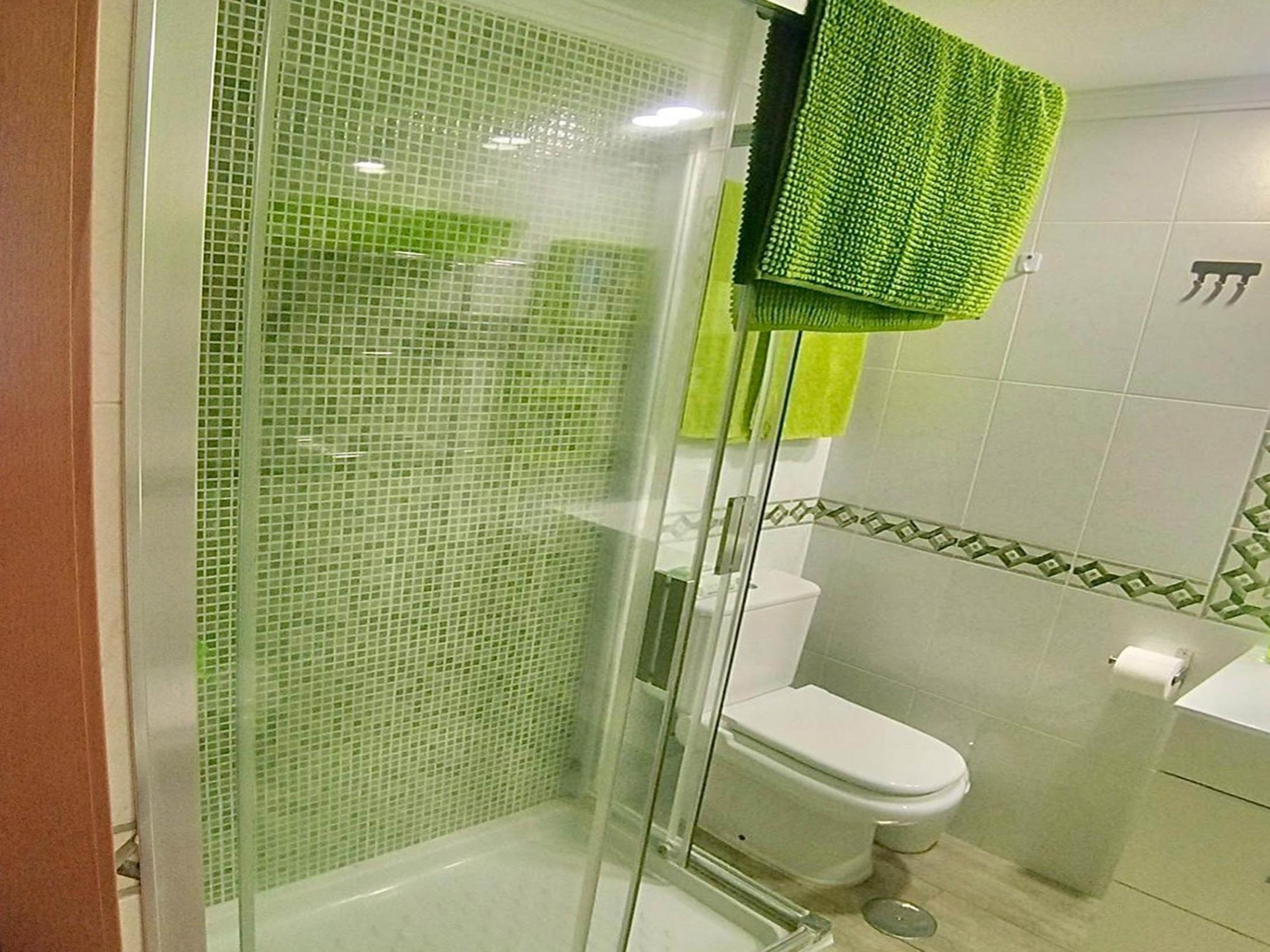 Une salle de bain avec une douche à parois de verre, des toilettes et un lavabo.