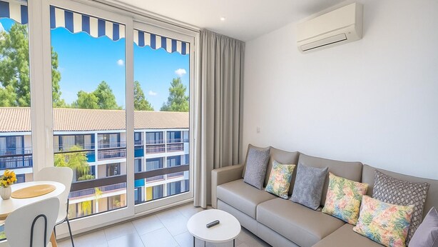 A modern living room with a sofa, a coffee table, and a dining area with chairs. - Apartamento Para so Ban s (Marbella)
