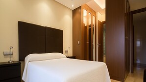 Una habitación de hotel con una cama grande, una mesita de noche, un escritorio y un armario.