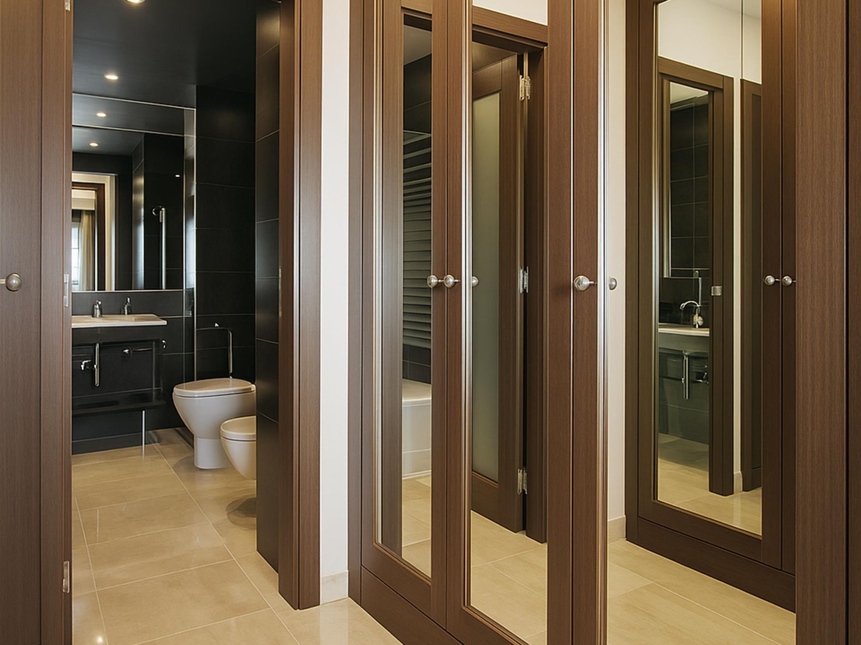 Un baño moderno con inodoro, bidé y un espejo grande.