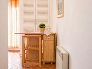A compact room with a wooden desk, a small cabinet, a radiator, and a potted plant. - Apartamento Acogedor en Primera Linea Liliane (Sitges)