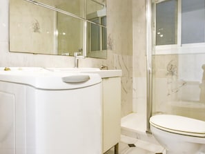 A modern bathroom with a white sink, mirror, and toilet.
