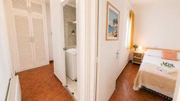 Habitación de hotel con cama, mesita de noche, un cuadro en la pared y un baño visible a través de una puerta abierta.