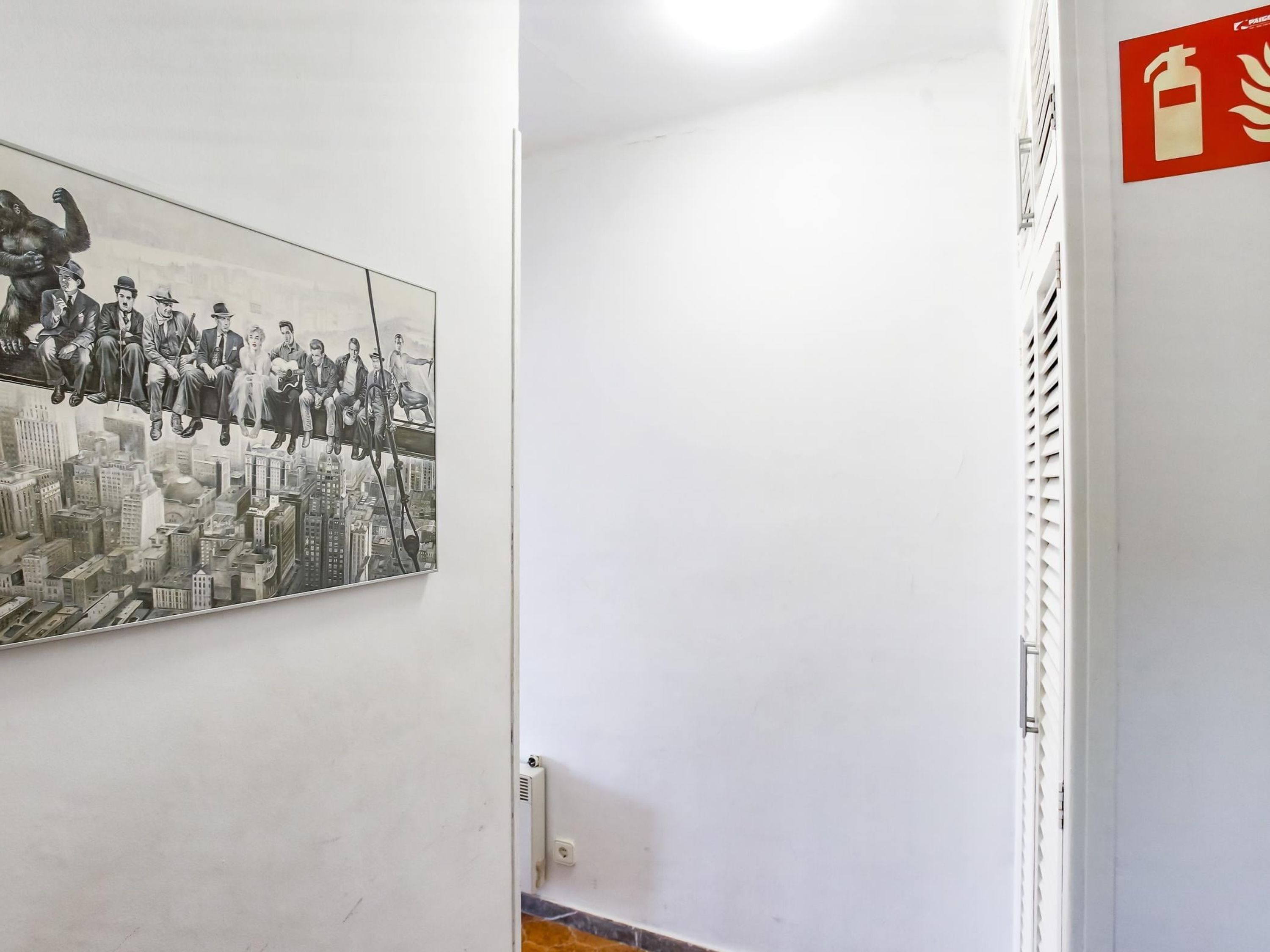 Un pasillo con un cartel de salida de incendios y una fotografía grande en blanco y negro en la pared.