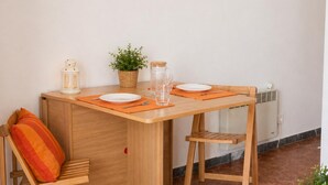 A compact dining area with a wooden table, two chairs, a small potted plant, a glass jar, and a white plate. - Apartamento Acogedor en Primera Linea Liliane (Sitges)
